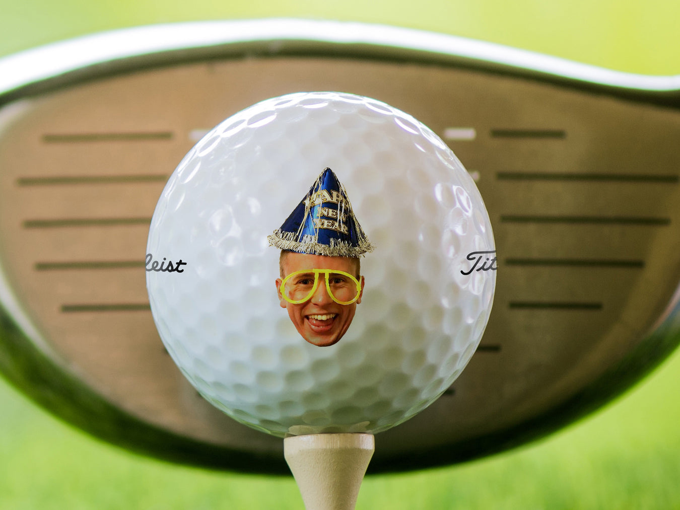 single white titleist golf ball on beige golf tee with golf club and grass in the background