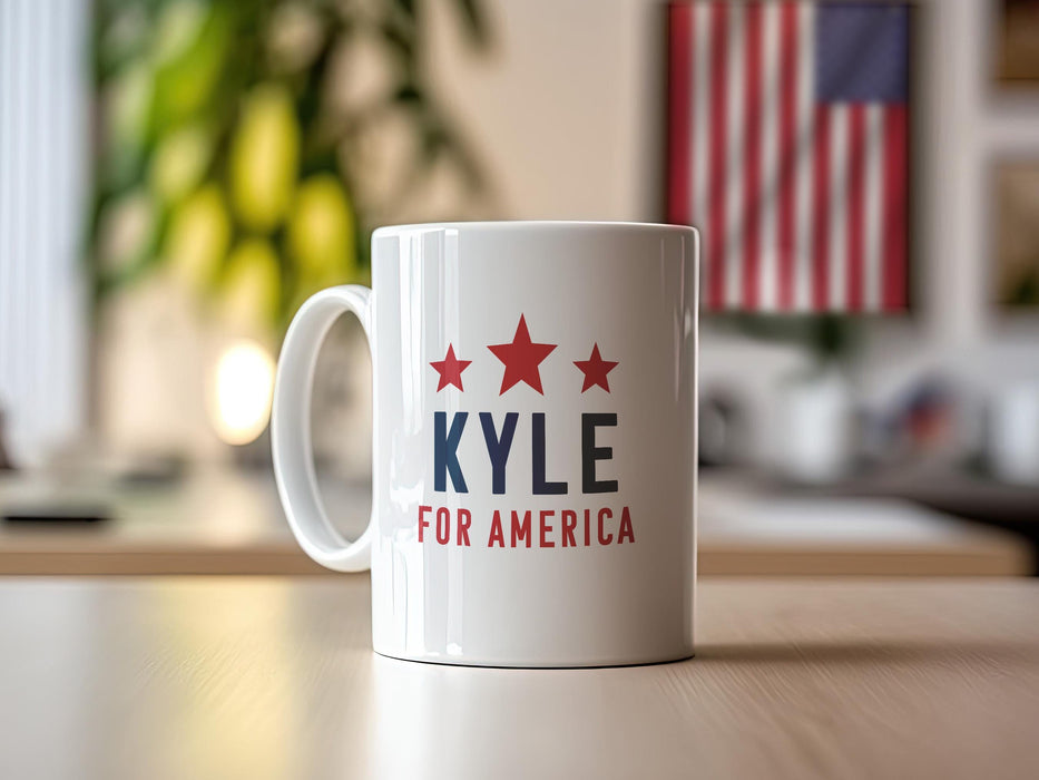 white mug with red white and blue American design with typography that says Kyle for America with Red Stars sitting in an office space with an American flag in the background