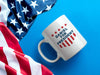 white mug with red white and blue American design with typography that says Daniel for America with Red Stars and Stripes sitting on a blue surface next to an American Flag