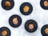 Multiple hockey pucks ontop of ice rink with first fathers day baby photo printed ontop with different names and colors