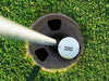 single white titleist golf ball with custom personalized established dad design in golf course hole next to pole surrounded by grass