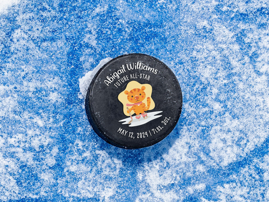 hockey puck ontop of ice with pink future all star cartoon tiger design with the name Abigail Williams on it with birthday and weight