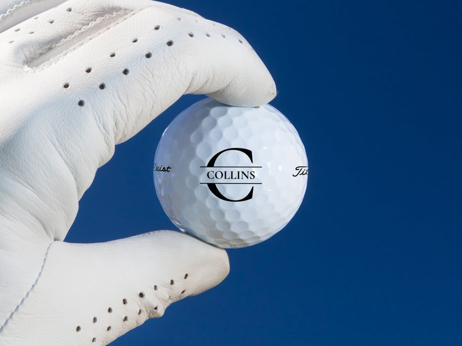 white gloved hand holding single white titleist golf ball with custom personalized black initial printed design against blue background 