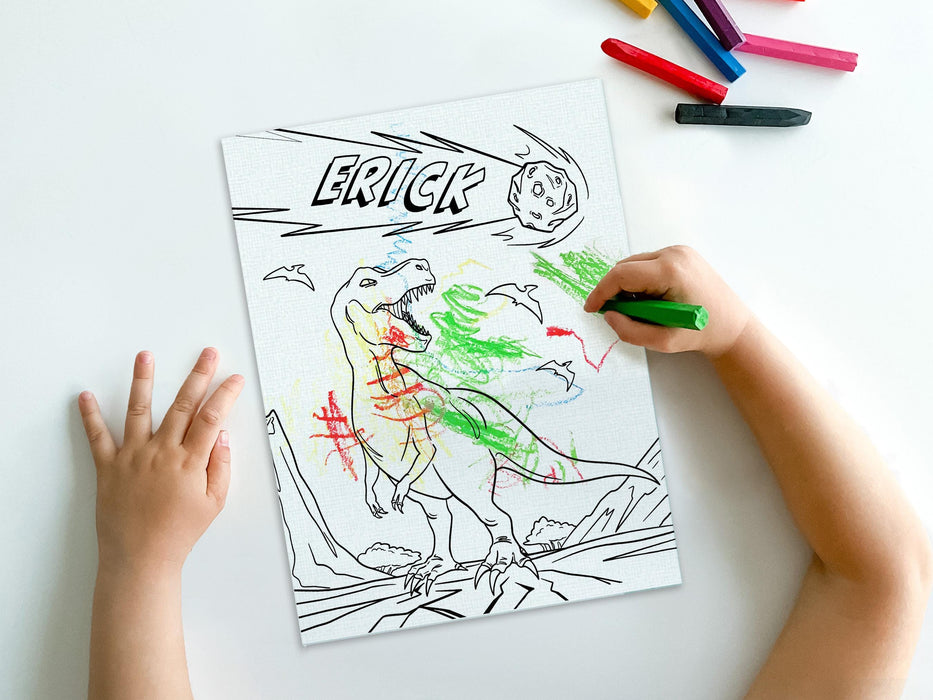 kid at white table coloring a canvas panel with a custom name dinosaur t-rex design printed on it using crayons with a pile of crayons right next to the canvas