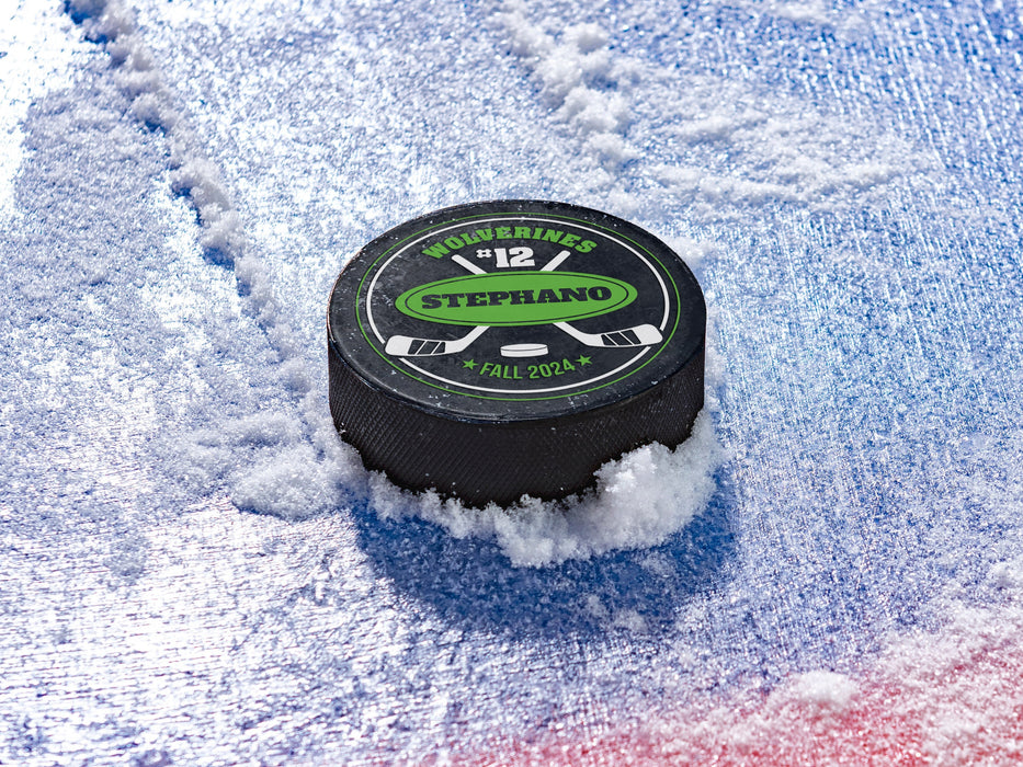 Hockey puck on ice rink with a green player and team name design with a hockey stick design with the words
Wolverines, 12, Stephano, Fall 2024