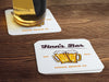 One coaster has a beer glass on it and an empty coaster sits beside it. Coasters feature bar design. This design uses brown and orange lettering, and a drawing of beer glasses. The name, established date, and location can be customized.