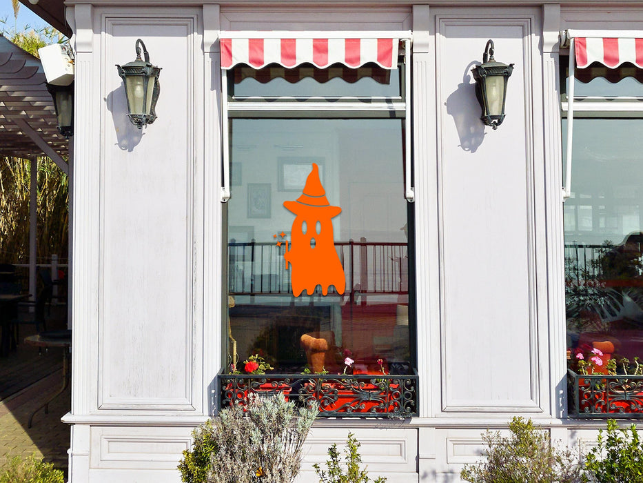 Ghost Witch sticker (in orange) is shown stuck to the exterior of a storefront window.