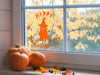 Happy Halloween Ghost sticker (in orange) is shown stuck to the interior of a window.