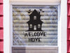 Haunted Welcome Home sticker (in black) is shown stuck to the exterior of a window.