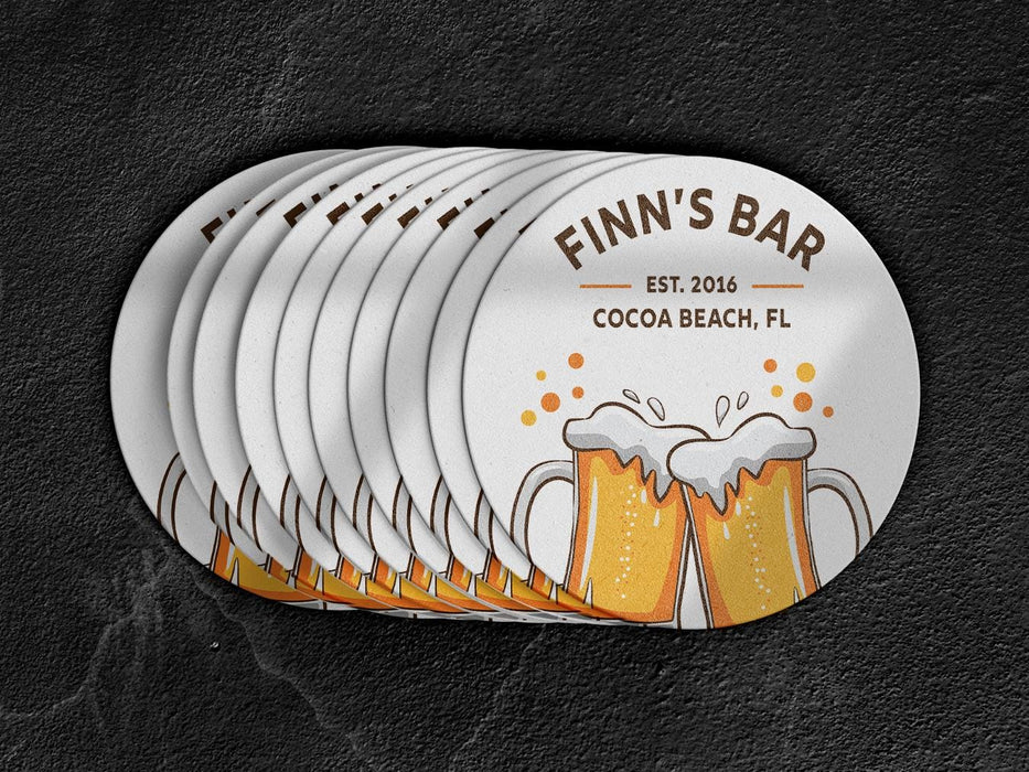 Coasters spread on top of a black surface. Coasters feature bar design. This design uses brown and orange lettering, and a drawing of beer glasses. The name, established date, and location can be customized.