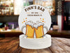 Single coaster sits on top of a stack of coasters. Coasters feature bar design. This design uses brown and orange lettering, and a drawing of beer glasses. The name, established date, and location can be customized.