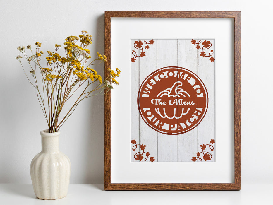 Welcome To Our Patch LIGHT STYLE design shown as digital download. Design has a pumpkin in the middle and pumpkin foliage on sides. The text on the design reads Welcome to Our Patch and The Allens. Design is in brown wooden frame.