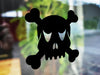 Skull and Crossbones sticker (in black) is shown stuck to the exterior of a window.