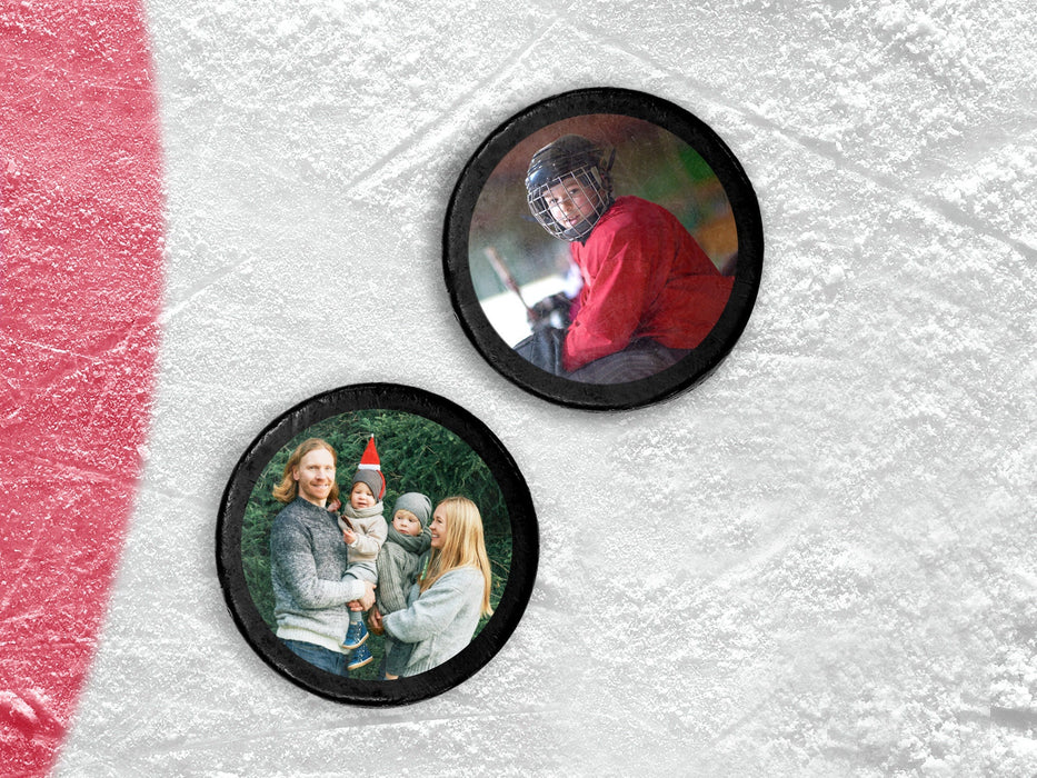 two hockey pucks with printed photos on top sitting on an ice rink