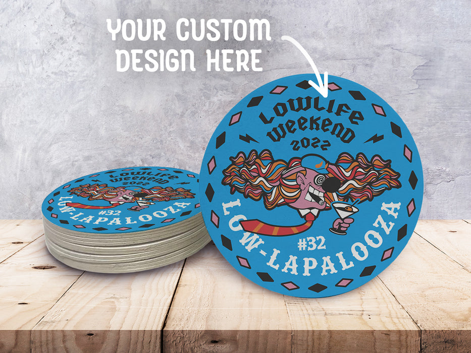 Your Custom Design Here and an arrow are pointed toward custom design coasters on a wooden surface. These coasters feature a submitted, custom design.