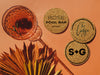 Three coasters with various designs sit next to drink on orange background.