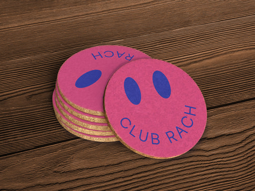 A close up of a stack of coasters on a wooden surface. The coasters are pink with blue detailing.