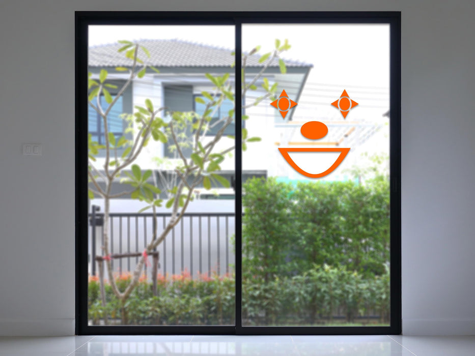 Clown sticker (in orange) is shown stuck to the interior of a glass door.