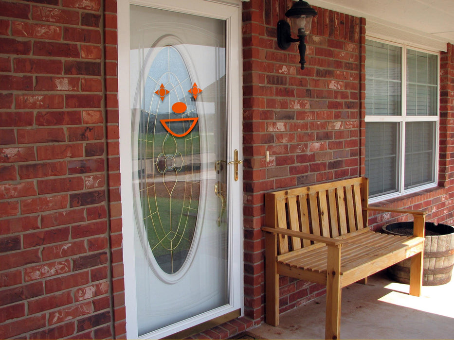 Clown sticker (in orange) is shown stuck to the exterior of a glass door.