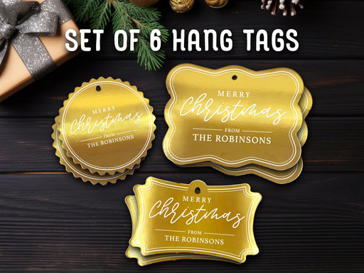 Text reads, Set of 6 Hang Tags. Six gold foil cardstock Merry Christmas hang tags are shown on a dark wooden surface. Pine tree branches, gold ornaments, and a Christmas present are shown around the tags.