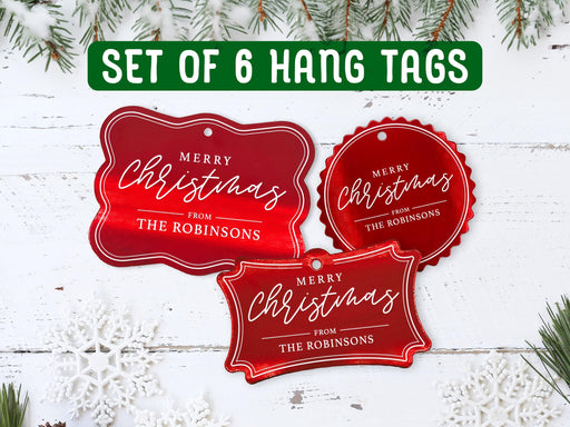 Text reads, Set of 6 Hang Tags. Six gold foil cardstock Merry Christmas hang tags are shown on a white wooden surface. Pine tree branches and snowflake surround the tags.