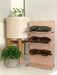 wooden glasses stand with multiple sunglasses sitting on a countertop surrounded by multiple potted plants