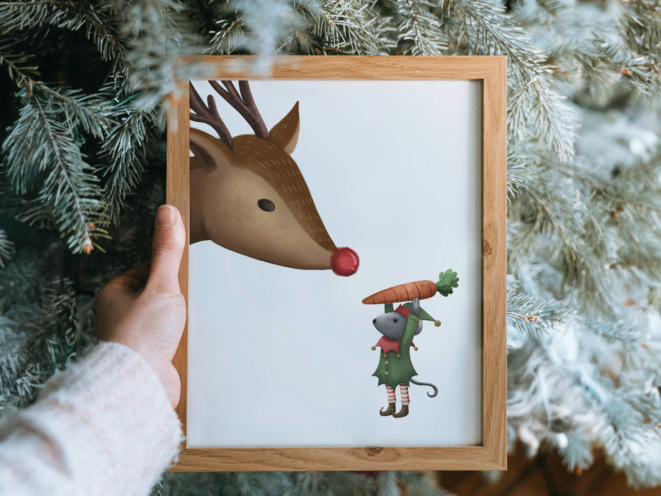 hand holding a wooden frame with a christmas print of a mouse decorating a tree in front of pine trees