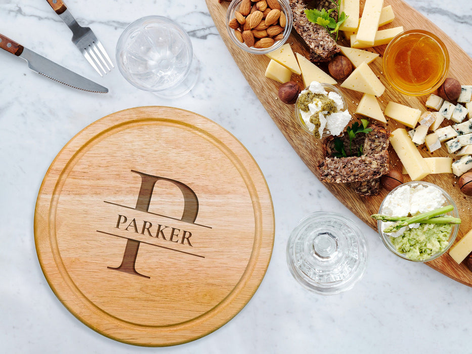 cheeseboard on marble table surrounded by tableware such as glasses, forks, knives, cheese, nuts, dips, and other charcuterie foods engraving includes the name Parker with the letter P