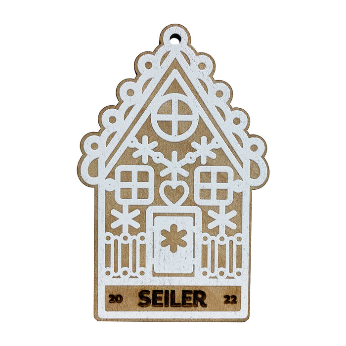 Ornament shown with Gingerbread House design. The ornament is wooden and shaped like a gingerbread house. A name and year are laser engraved into ornament.