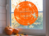 happy halloween family name vinyl sticker on window next to pumpkins and fall leaves