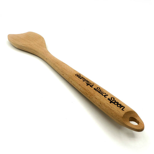 Laser engraved flat wooden spoon that says Grammys Sauce Spoon on handle against white background