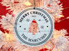 Ornament shown hanging from a Christmas tree. The ornament is wooden and shaped like a circle with a Christmas Tree cutout in the middle. Ornament says Merry Christmas, Year, and Family Name