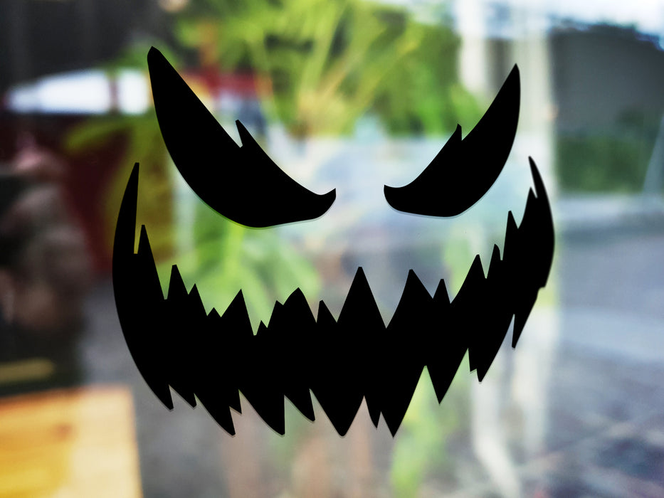 black scary pumpkin face vinyl sticker in front of blurred background