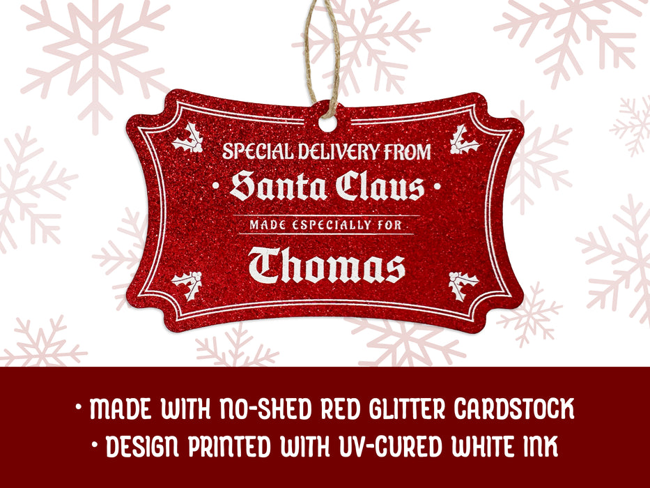 A red glitter hanging cardstock Santa gift tag is shown on a white background with red snowflakes. Text underneath the tag reads: Made with no-shed red glitter cardstock, Design printed with UV-cured white ink.