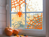 spider web vinyl sticker on indoor window next to pumpkins and fall leaves 