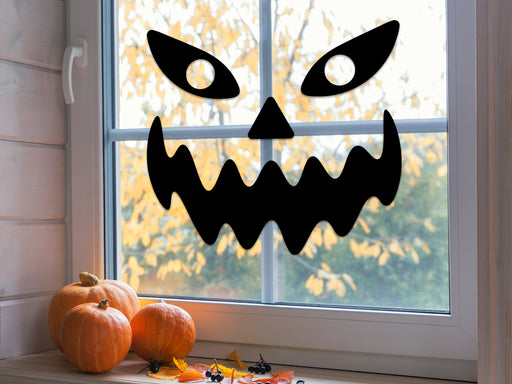 spooky pumpkin face silhouette placed on a window next to pumpkins