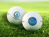 two golf balls with logos printed on them sitting on golf course grass